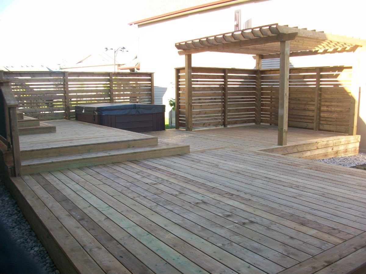 Backyard with a cedar pergola, hot tub and privacy screen at golden hour
