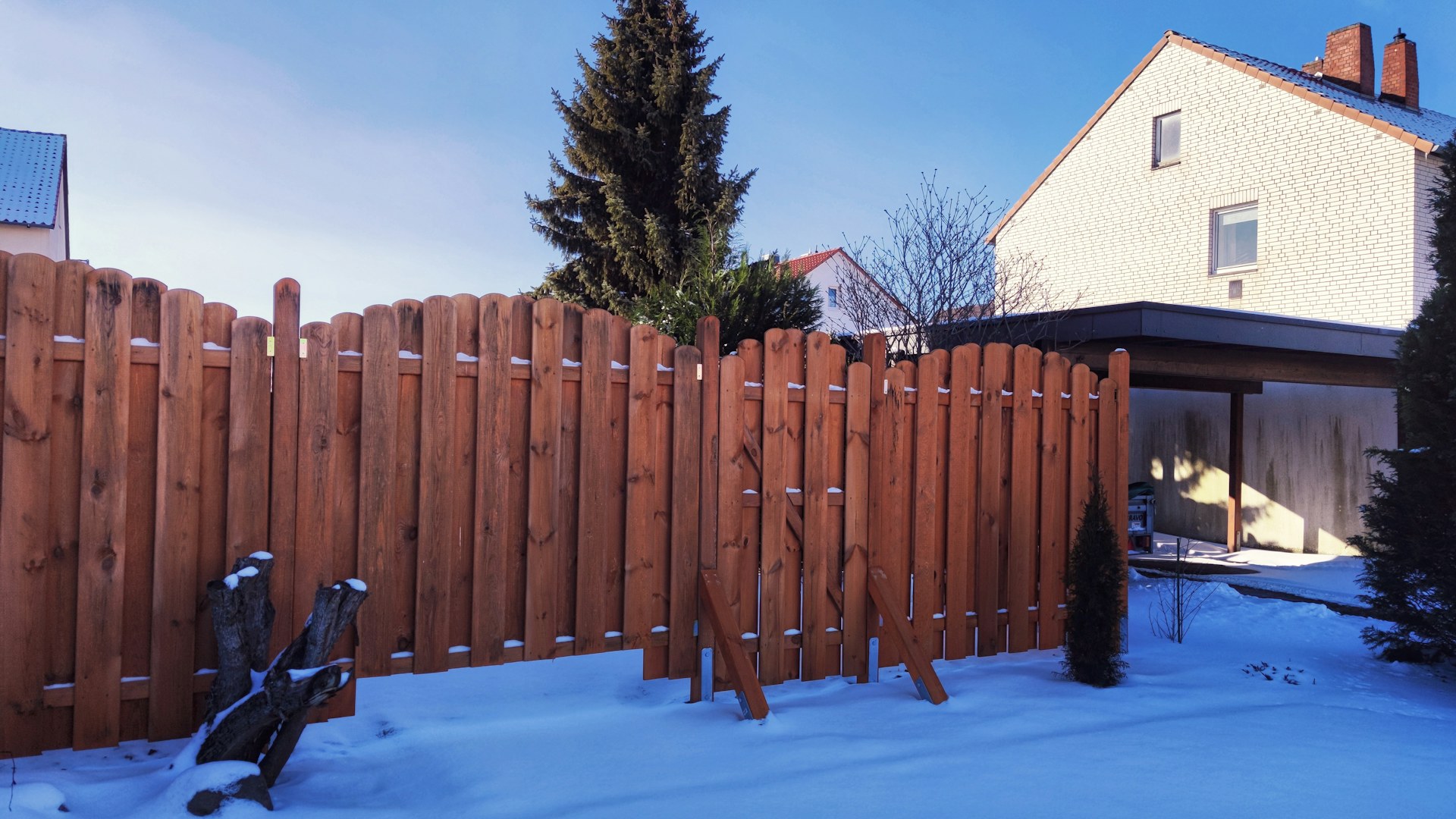A stained cedar privacy fence beside a home in fresh snow, built to last through Ottawa winters