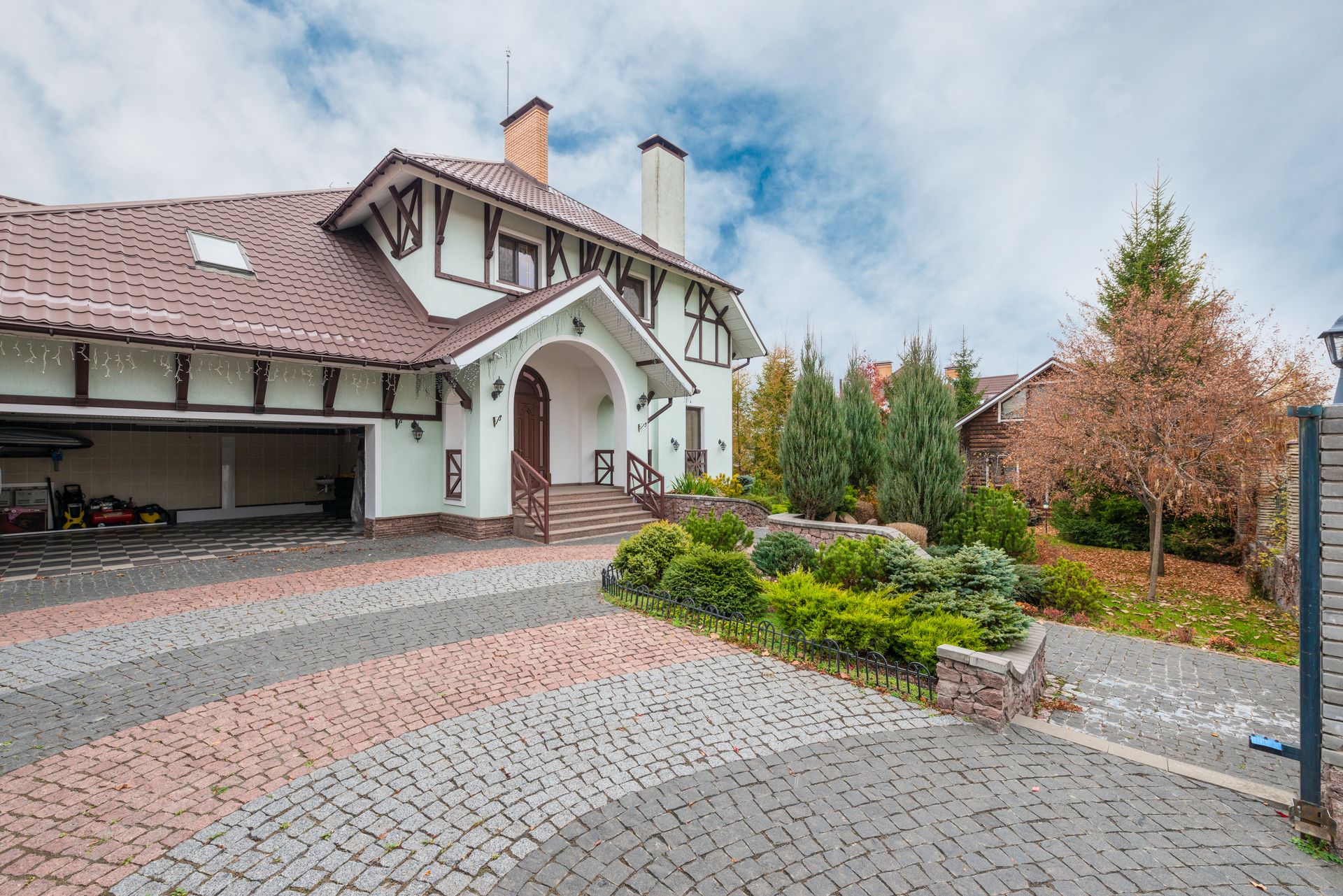 A patterned interlock stone driveway with a stone retaining wall and layered landscaping at a residential home