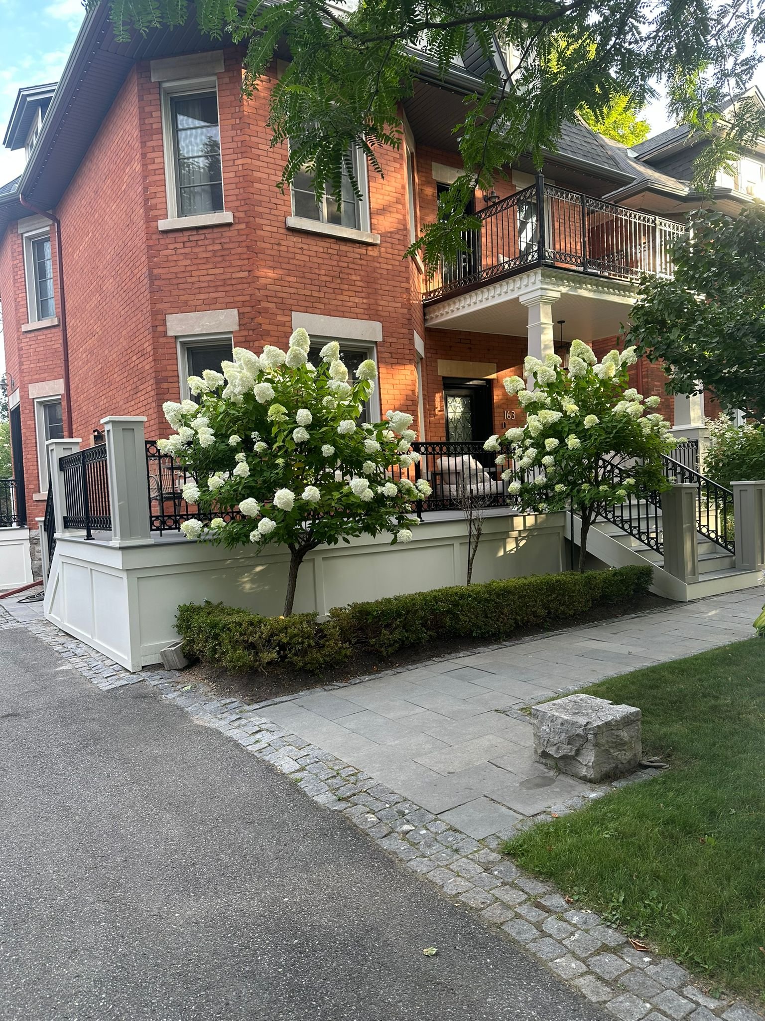 Large-format interlock paver walkway with cobblestone borders and hydrangea landscaping at a brick Ottawa home