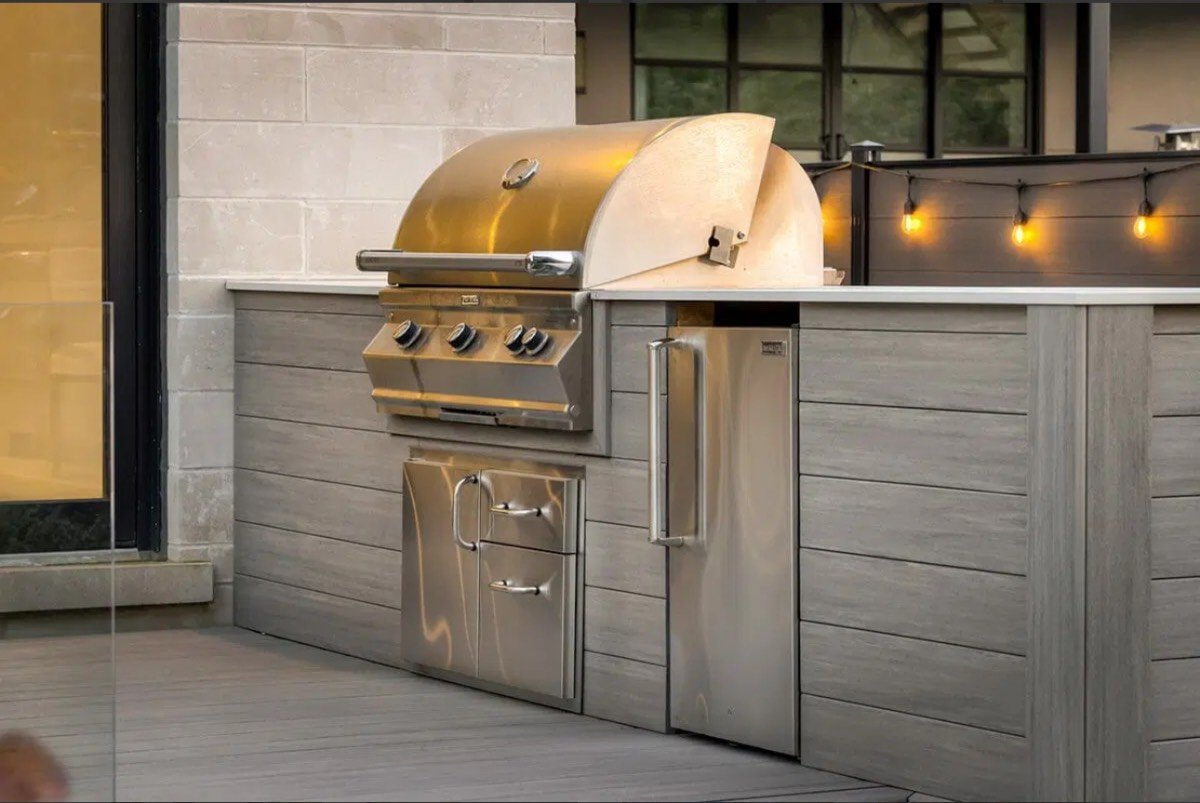 Outdoor kitchen with composite cabinetry and string lights at golden hour