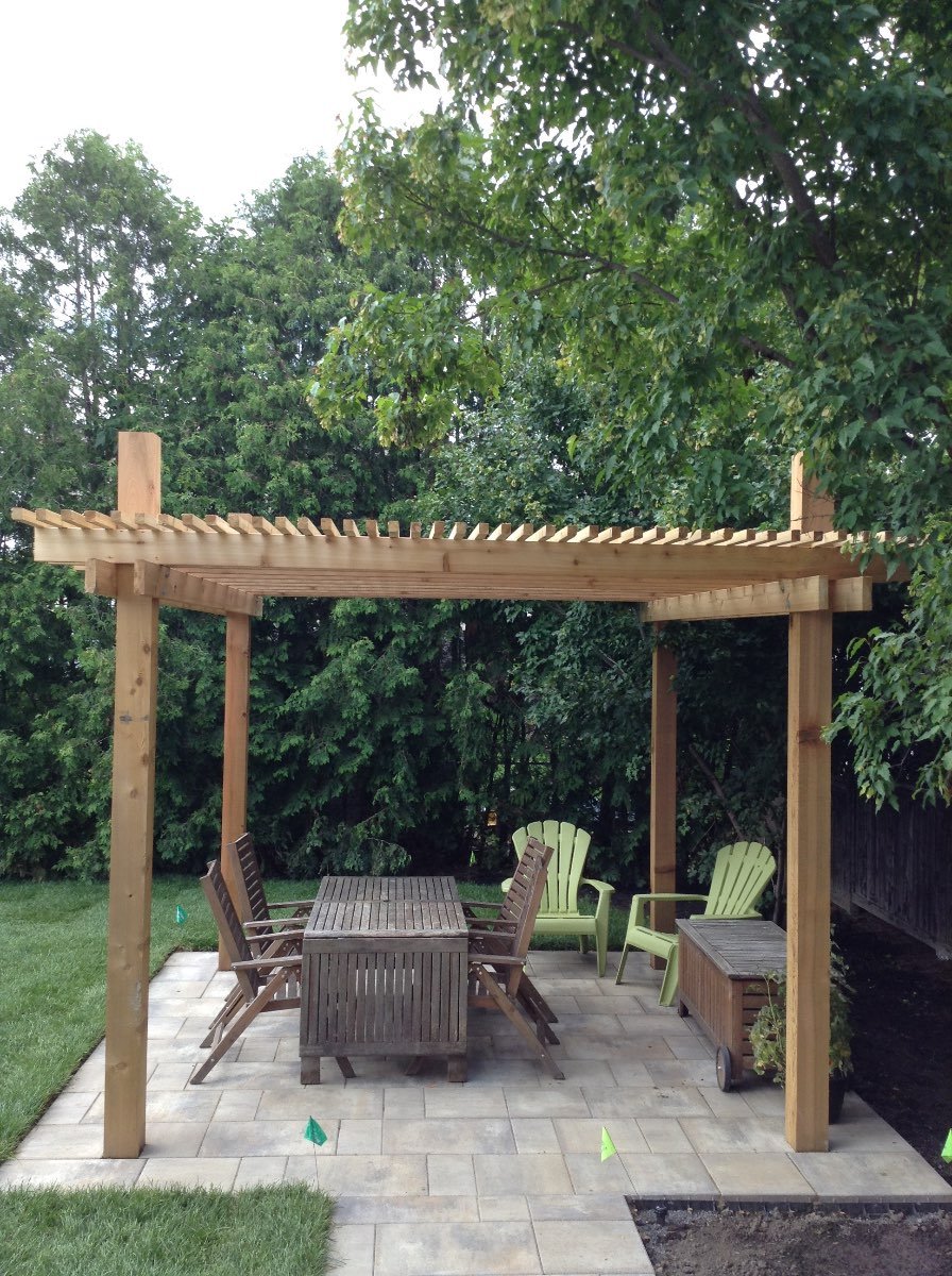 Cedar pergola over an interlock stone patio with a dining set